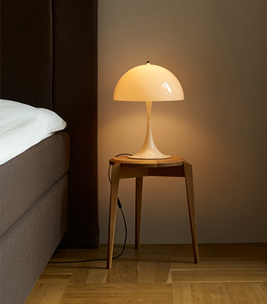Klassisk nattbordslampe i soppform som sprer et mildt lys i et koselig soverom