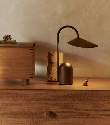 Elegant bordlampe med skulpturell design på et tresidebord i mykt omgivelseslys