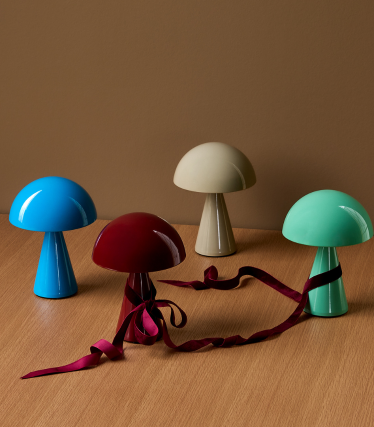 En minimalistisk stue med Spokes pendellampe fra Foscarini som et elegant midtpunkt. Lampens filigrane, metalliske stag kaster myke lysmønstre på veggen og taket, og gir rommet en lett, skulpturell effekt. Lys sofa, mørke aksenter og naturlige materialer skaper en rolig, moderne atmosfære