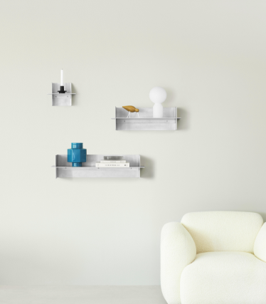 Gjennomsiktige Normann Copenhagen veggskap med dekorative tilbehør i et minimalistisk oppholdsrom.