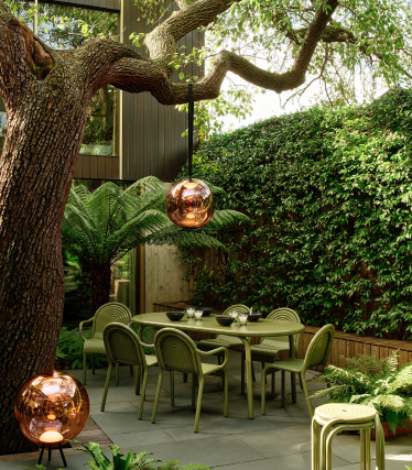 Tom Dixon utelamper i stilfull hage med spiseområde under gammelt tre.