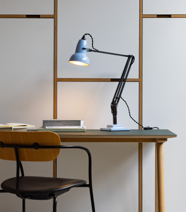 Lyseblå Anglepoise skrivebordslampe på et trebord med stol