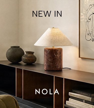 Nola-bordlampe med rødbrun marmorfot og konisk skjerm i lin på en mørk skjenk. Tekst: «Nyhet – Nola».