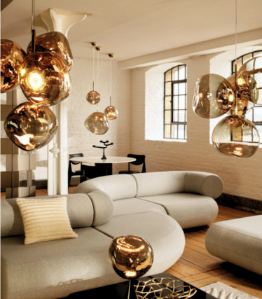 Gullfargede Melt-pendler over en lys sofa i en loftsleilighet med sprossevinduer.